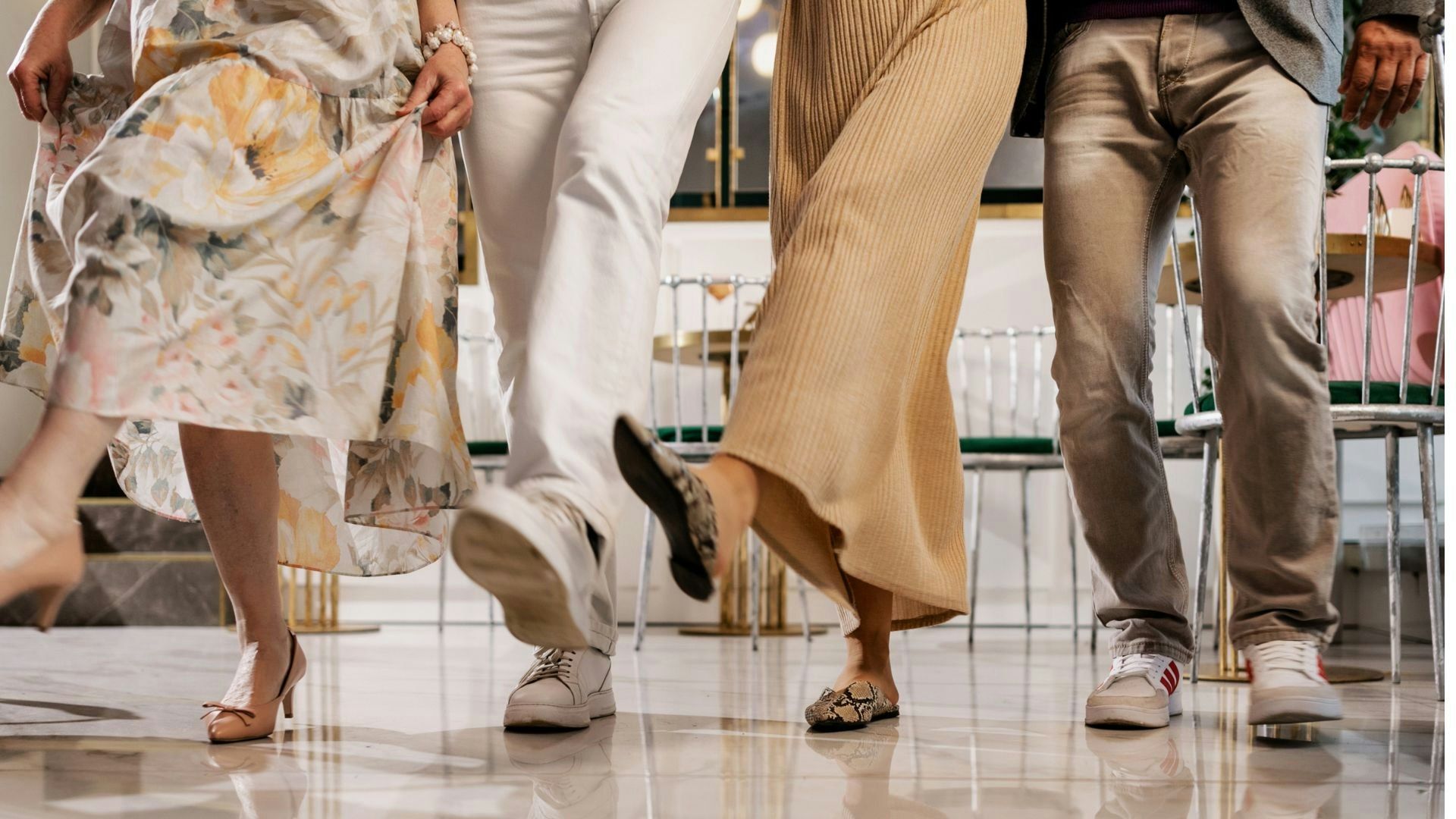 A group of people is seen dancing or moving together, showcasing their stylish footwear against a stylish backdrop.