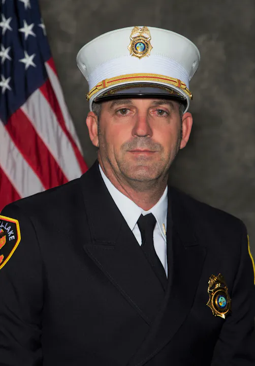 A uniformed firefighter with an American flag backdrop.