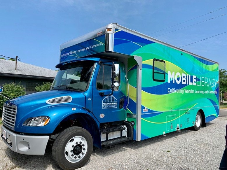 A blue and green mobile library truck with the text "Cultivating Wonder, Learning, and Community."