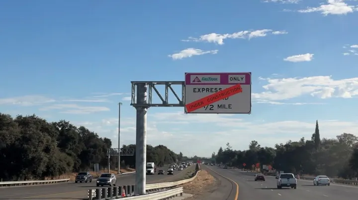 A highway sign indicating an express lane for FasTrak only is under construction in half a mile.