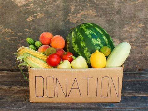 A box labeled "DONATION" filled with fresh fruits and vegetables against a wooden background.