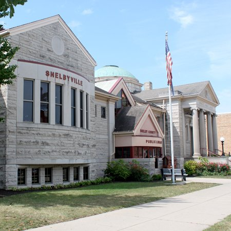 A library building with an American flag, labeled "Shelby County Public Library" in Shelbyville.
