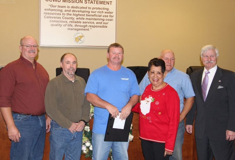 Five individuals posing for a photo in a room with a "CCWD MISSION STATEMENT" sign.