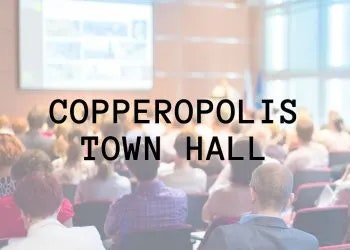 A blurred image of a group of people at a town hall meeting with the text "Copperopolis Town Hall."