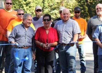 Group of people at a ribbon-cutting ceremony, some in hi-vis gear, others holding scissors, smiling for a celebratory moment.