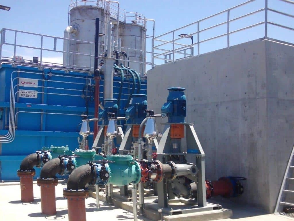 Industrial water treatment facility with pipes, tanks, and pumps.