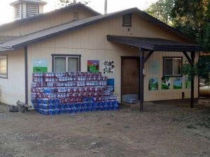 A house with a wall partially covered in colorful square patterns which appear to be made from soda can boxes.