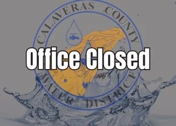 A sign indicating an office in Calaveras County is closed, with a water-themed graphic and county seal.