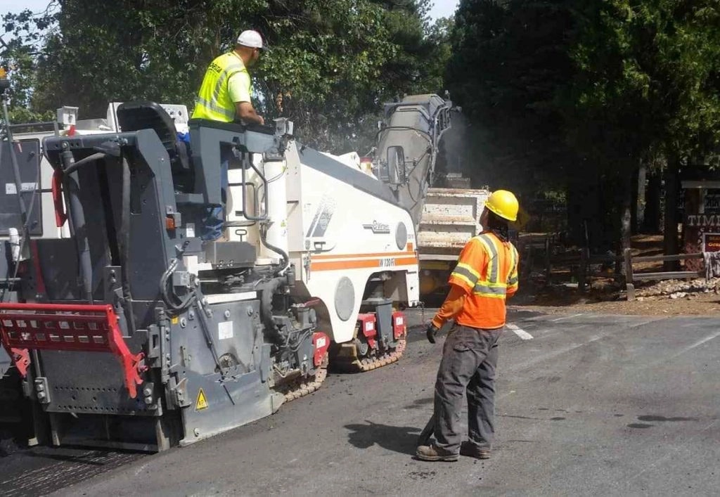 Road construction with workers and paving equipment.