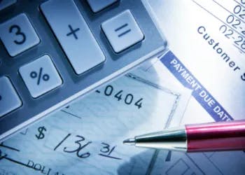 A calculator, pen, and financial documents suggesting bill payment or accounting work.