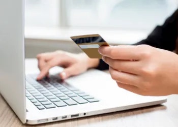 Person online shopping or banking with a credit card and laptop.