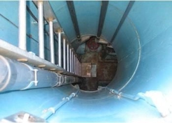 Inside of a cylindrical structure with pipes and metal supports, likely industrial.