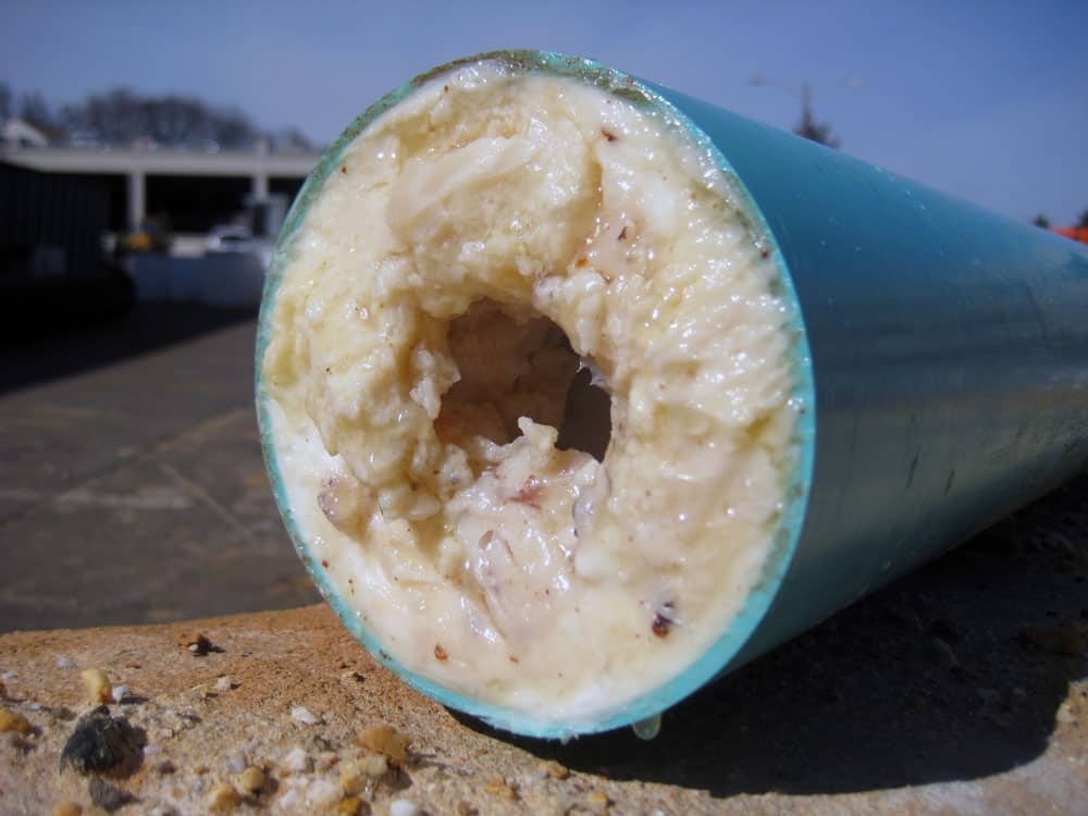 A clogged pipe with a buildup of congealed grease and waste.