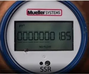 A digital water meter reading "0000000.185" with "NO FLOW" status displayed, indicating no water usage at the moment.