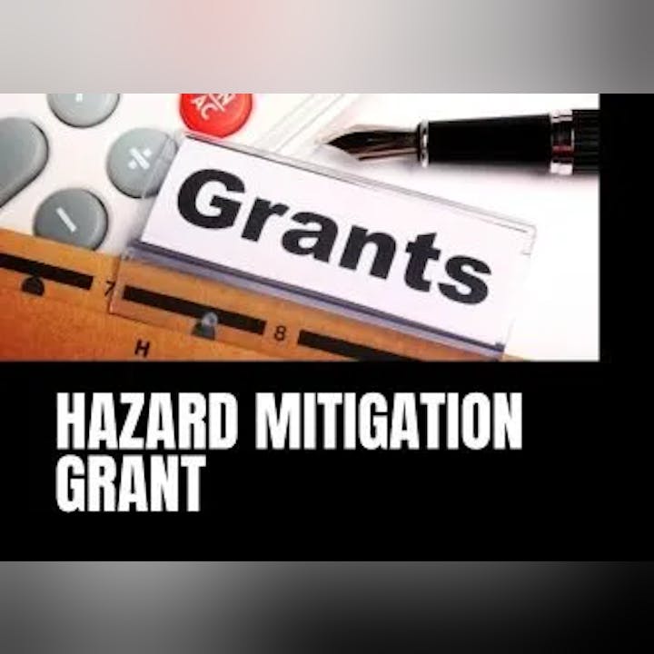 Folder labeled "Grants," calculator, pen, "HAZARD MITIGATION GRANT" text.