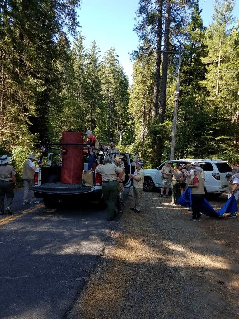 Group of people, possibly park rangers, gathered around a truck in a forested area.