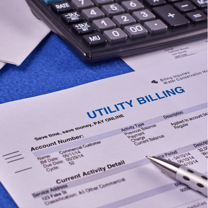 Utility bill with a calculator and pen on a blue surface.
