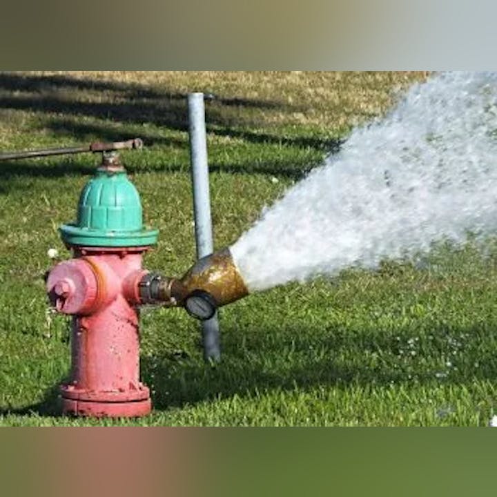 A fire hydrant spraying water onto grass.