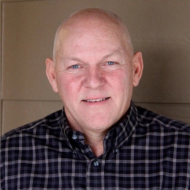 Bald man with a smile, wearing a checkered shirt.