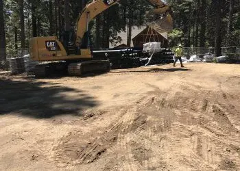 A construction site with an excavator and a worker in a safety vest.
