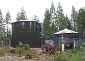 Two industrial water tanks in a wooded area.