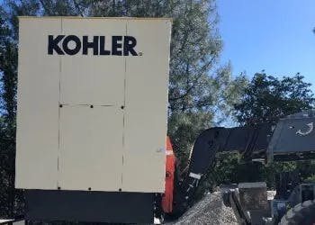A Kohler generator next to construction machinery in an outdoor setting.