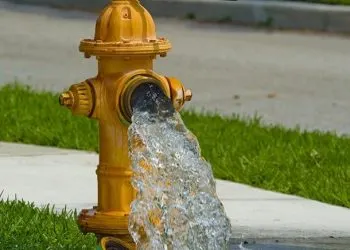 A yellow fire hydrant with water gushing out.