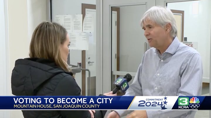A reporter interviews a man with a microphone labeled KCRA, with on-screen text about Mountain House voting to become a city.