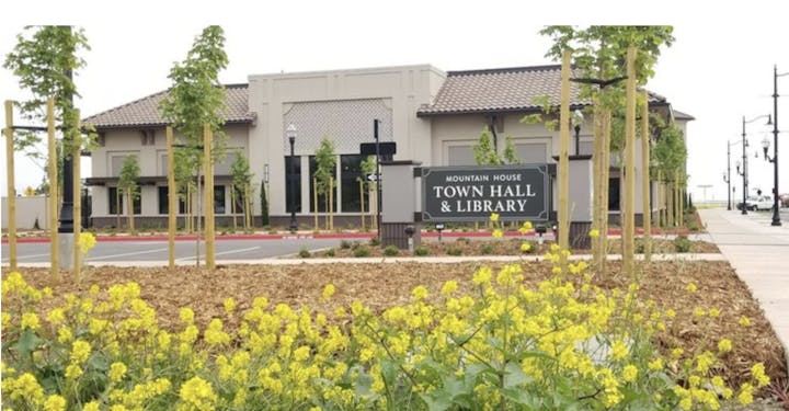 A new town hall and library building with landscaping, signage, and a sidewalk.
