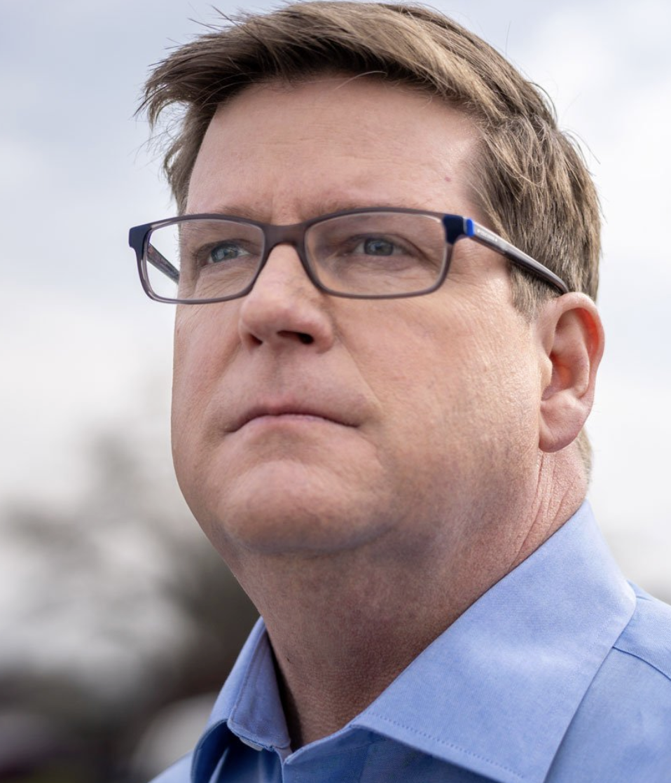 Close-up of a man with glasses looking to the side.