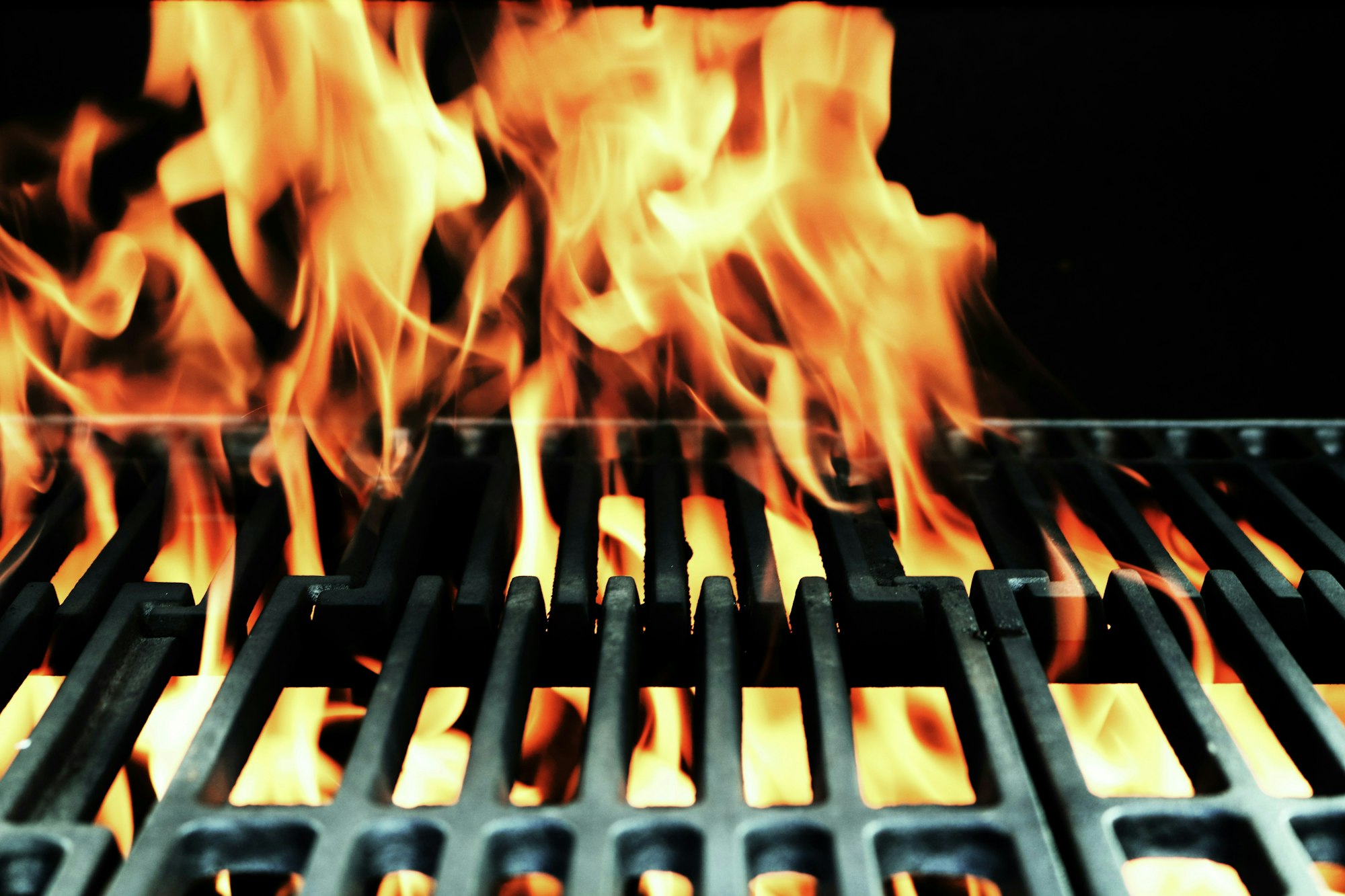 Flames rising from a barbecue grill with glowing orange and yellow colors.