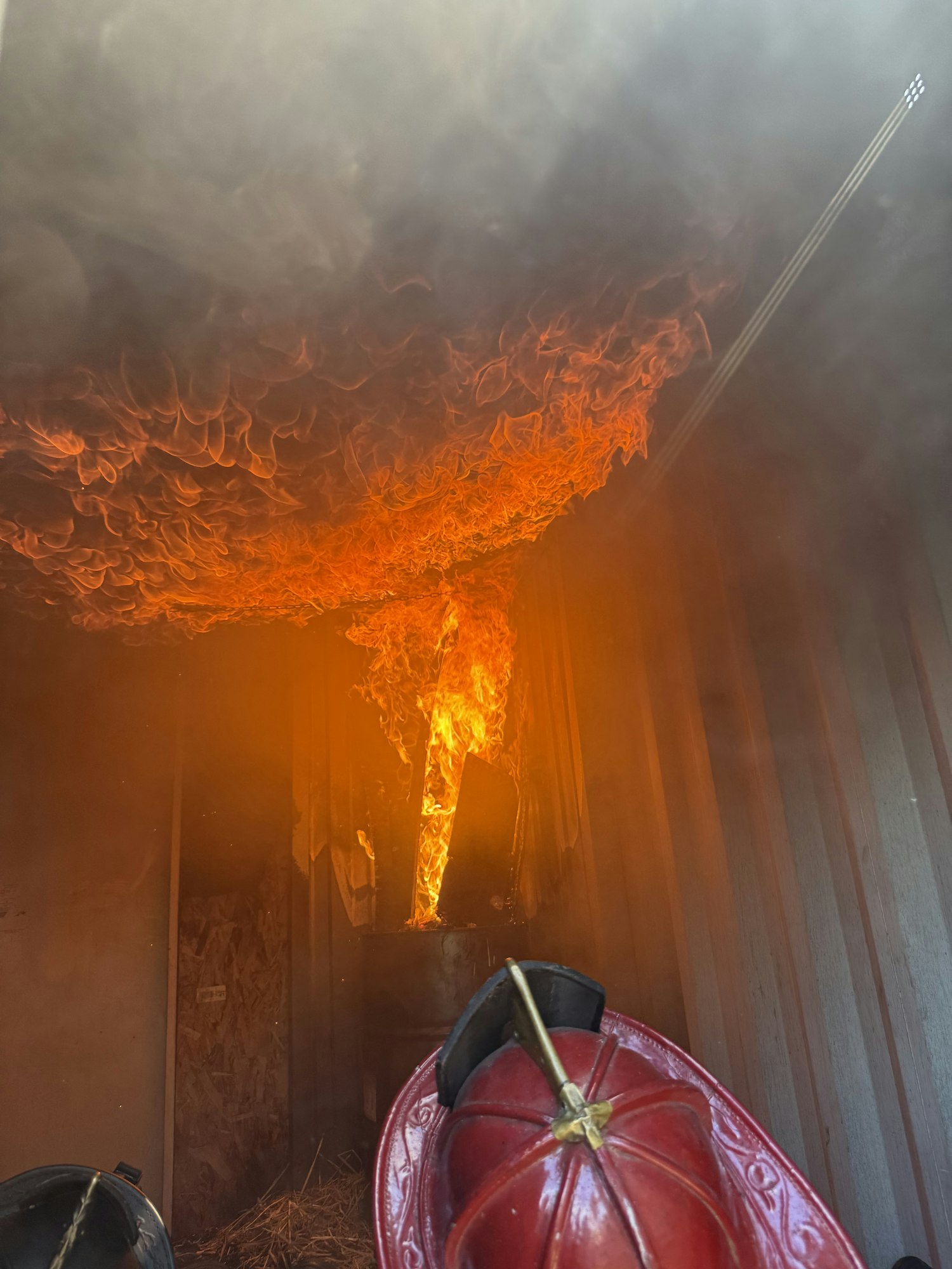 The image shows a scene of flames in a smoky environment, likely depicting a fire emergency or training scenario.