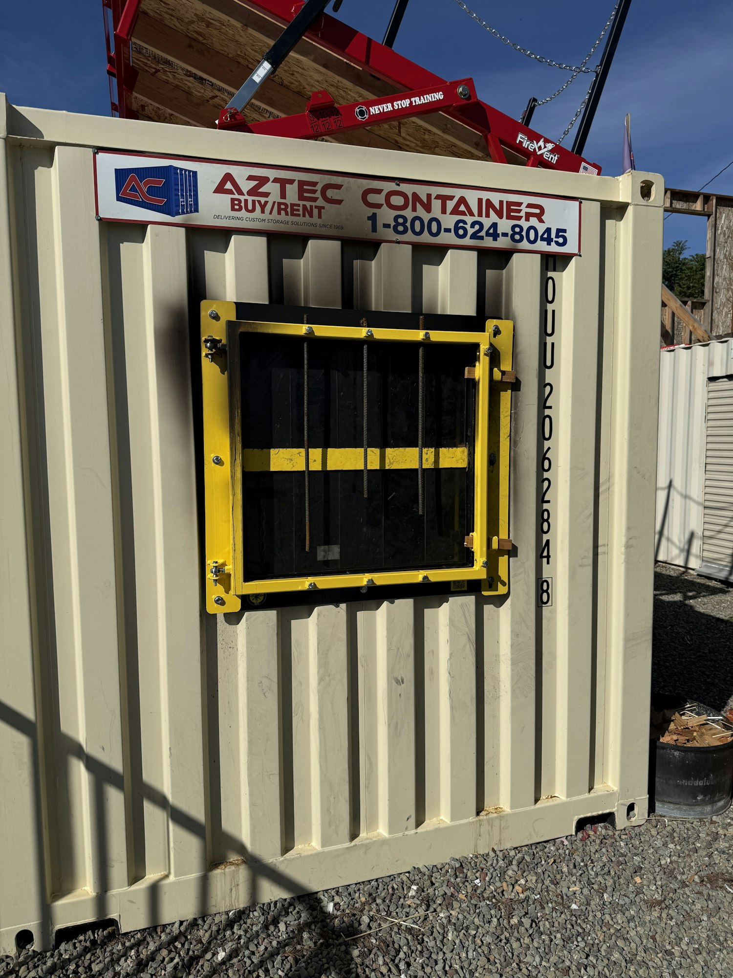 The image shows a storage container with a yellow window and a sign for Aztec Container rental services.