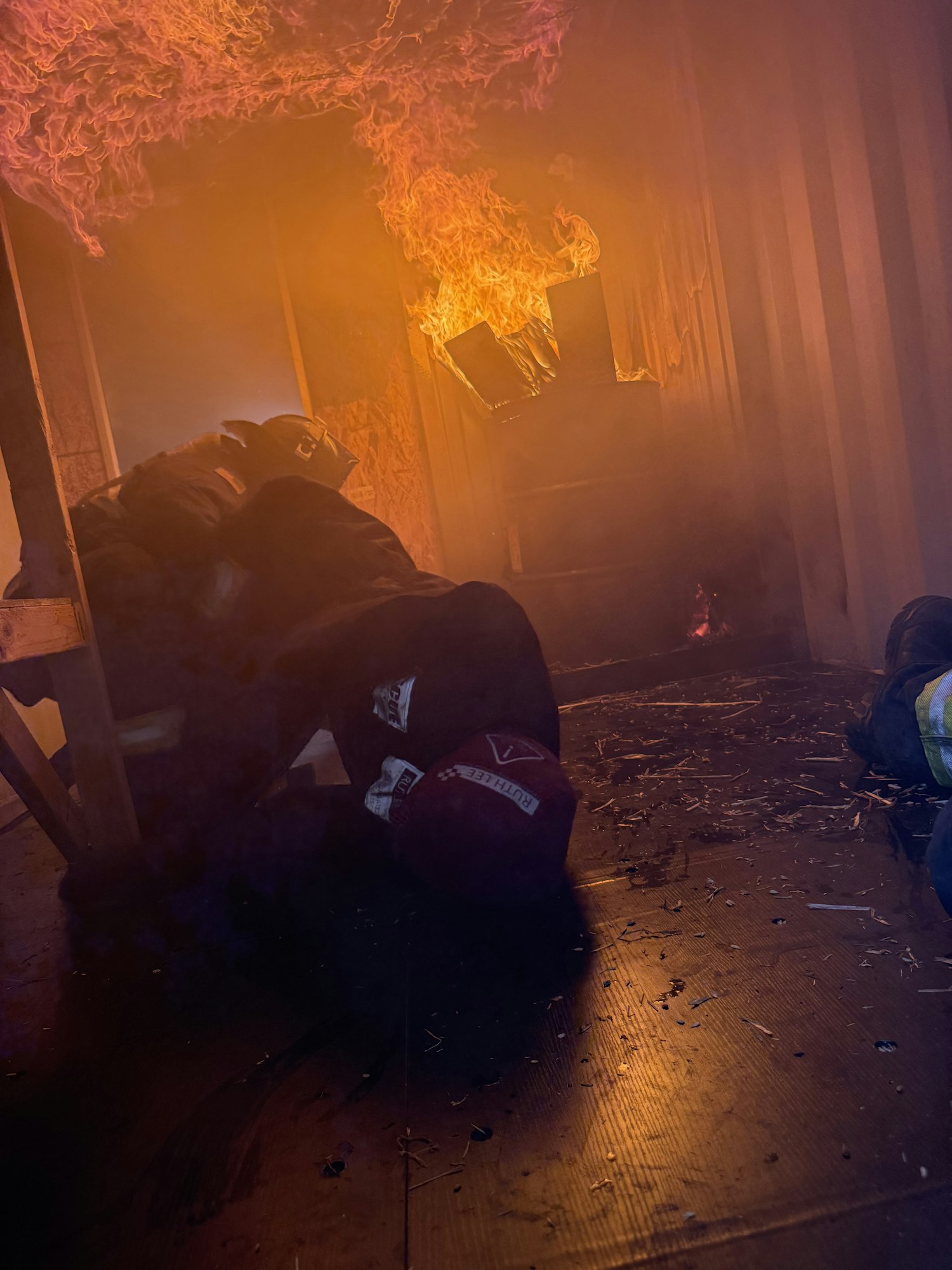 The image shows a smoky environment with flames and a person, possibly a firefighter, working amidst the fire.