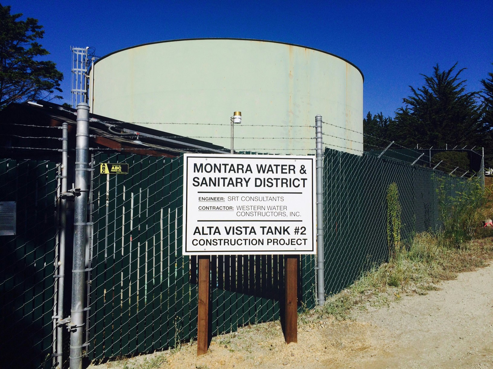 Sign for Montara Water & Sanitary District's Alta Vista Tank #2 construction project with fenced area and tank in the background.