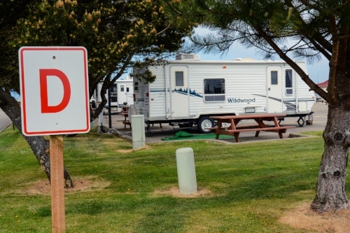 May contain: caravan, transportation, van, vehicle, grass, plant, desk, furniture, table, tree, architecture, building, housing, truck, house, and mobile home