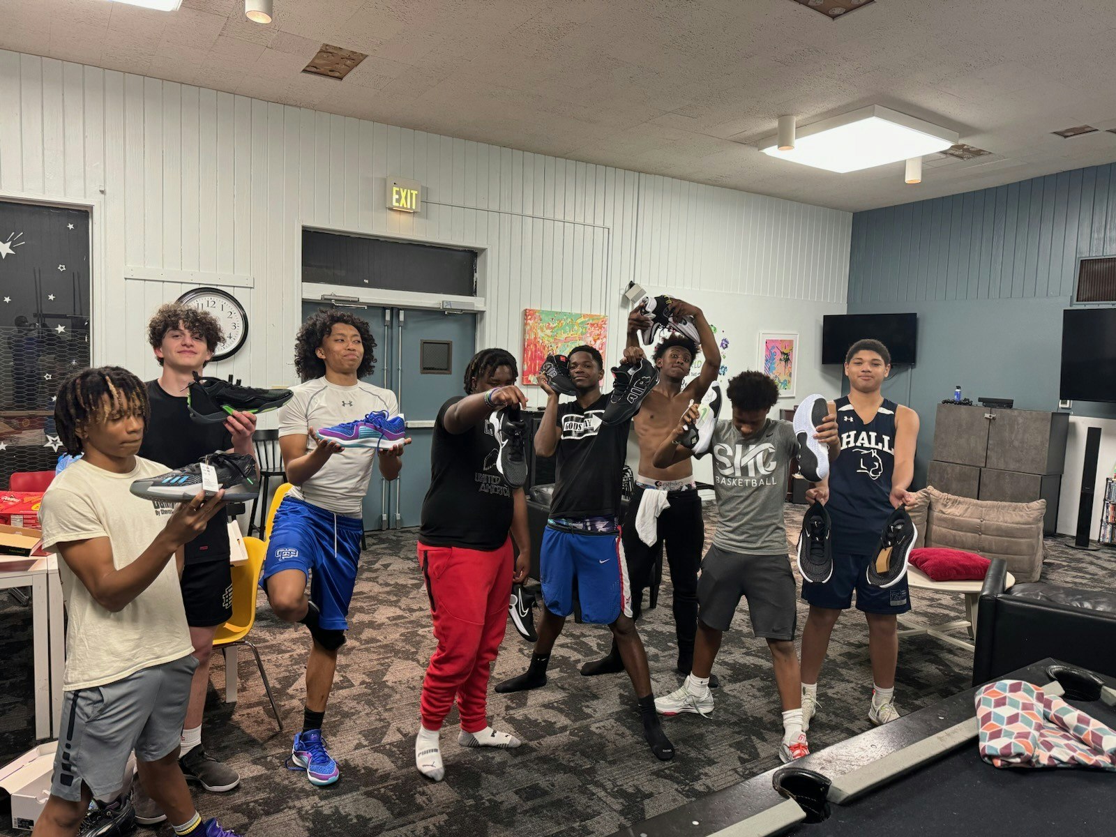 Group of people posing with athletic shoes indoors.