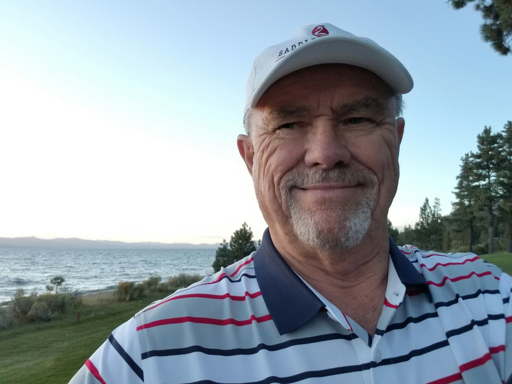 May contain: face, head, person, photography, portrait, baseball cap, cap, clothing, hat, grass, plant, shirt, accessories, glasses, adult, male, man, t-shirt, tree, vegetation, nature, outdoors, sea, and water