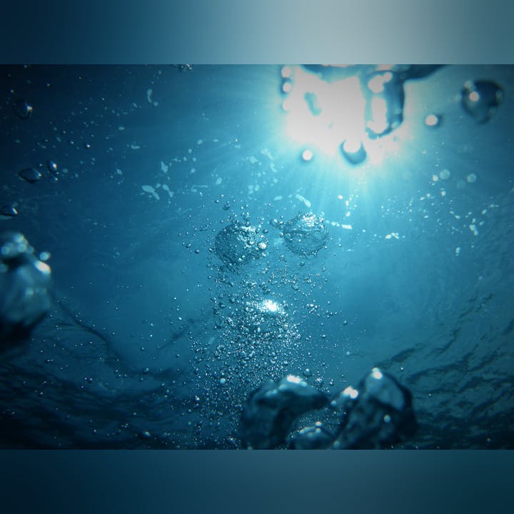 Underwater view with bubbles rising toward the surface, illuminated by sunlight filtering through the water.