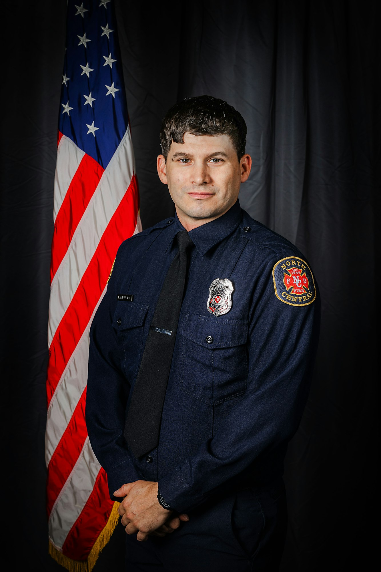 Firefighter in uniform in front of US flag.