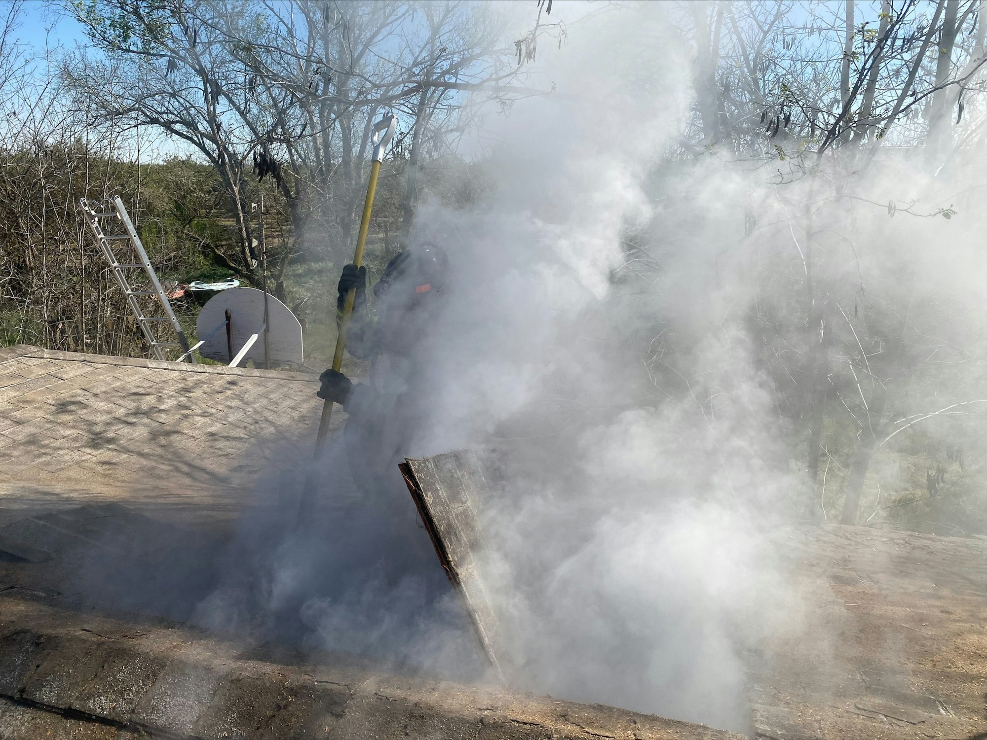 Smoke venting from a hole made in the roof of a house fire