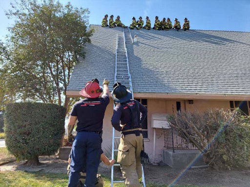 Firefighters sitting on the peak of a roof.