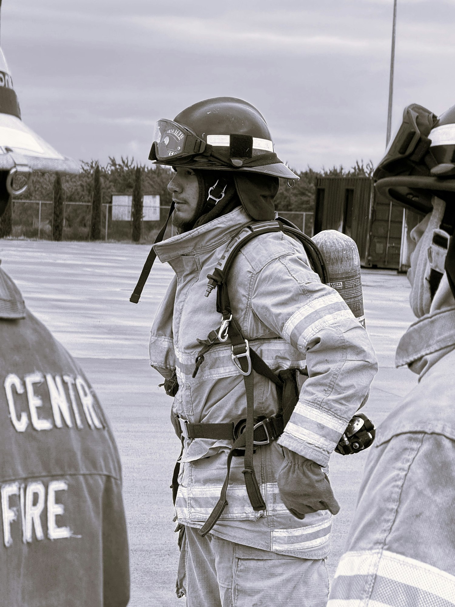 Firefighters in full gear, standing outdoors, likely preparing for or discussing a task.