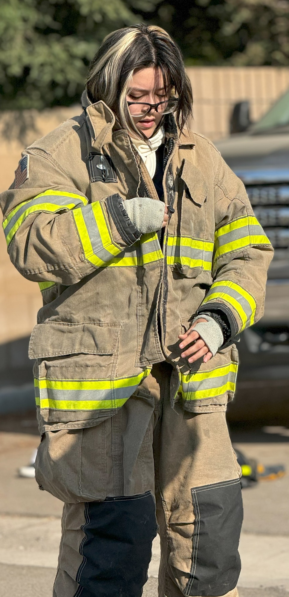 Person wearing firefighter gear, standing outdoors.