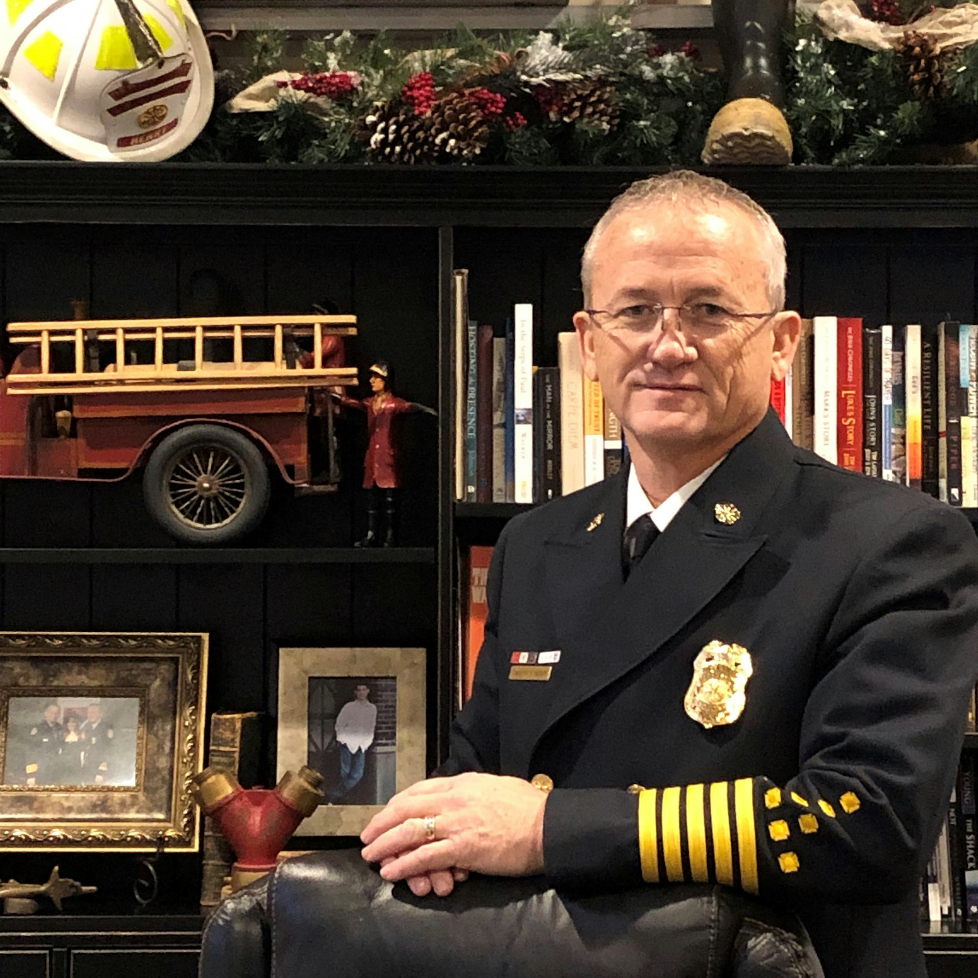 The Fire Chief in dress uniform standing by office bookcase.