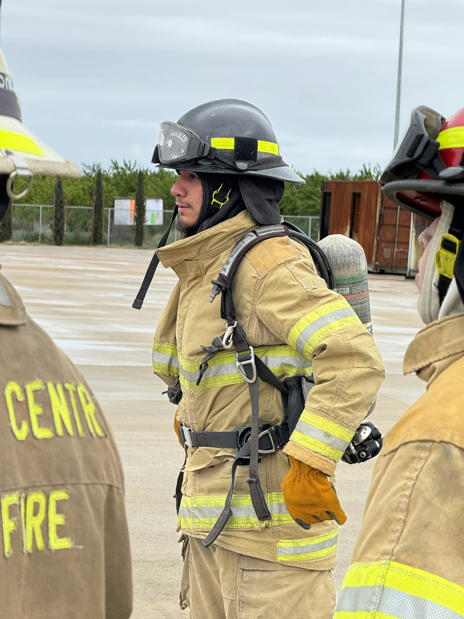 Firefighters in gear with helmets and oxygen tanks, outdoors.