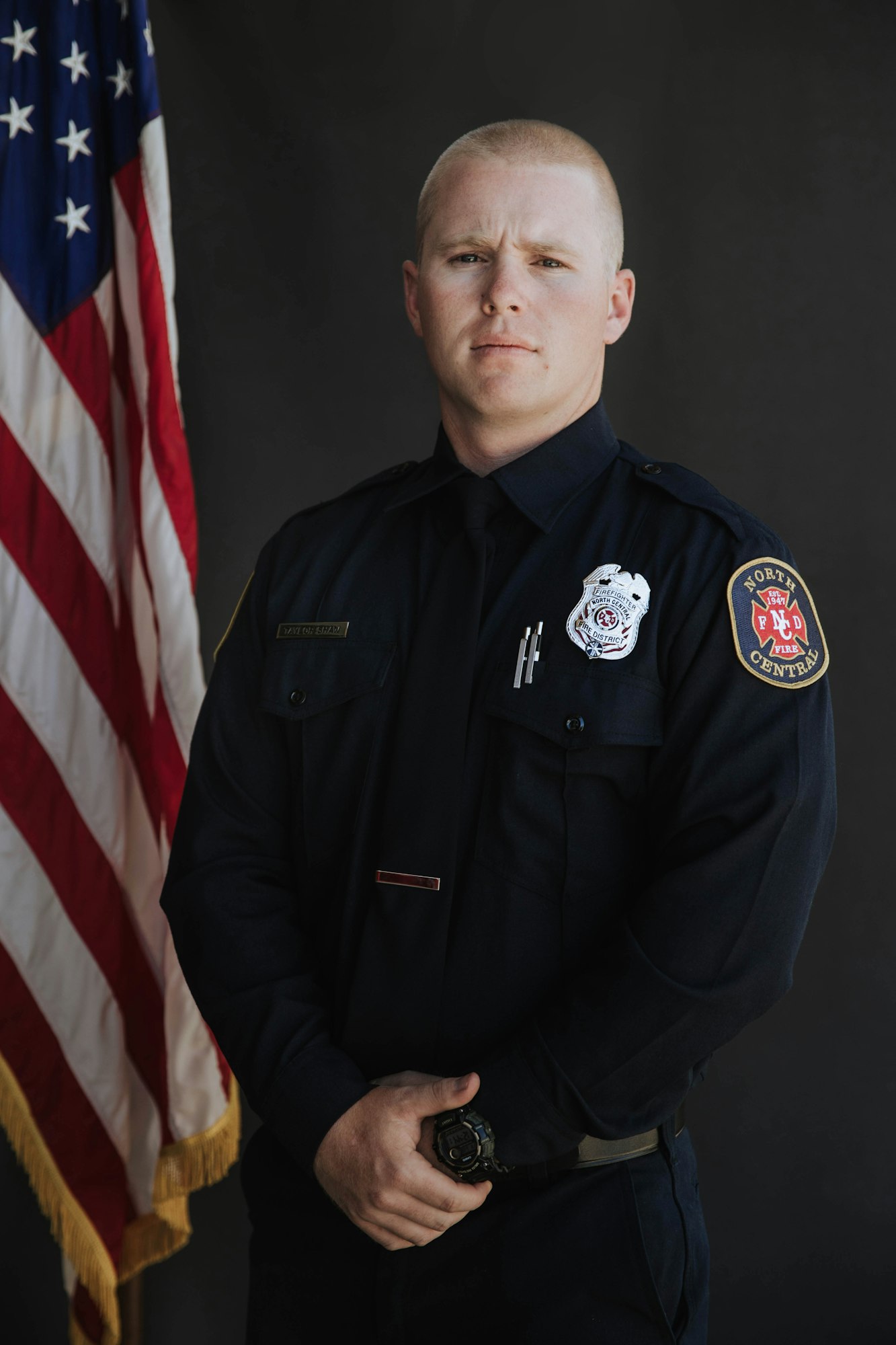 A uniformed firefighter poses in front of a U.S. flag.