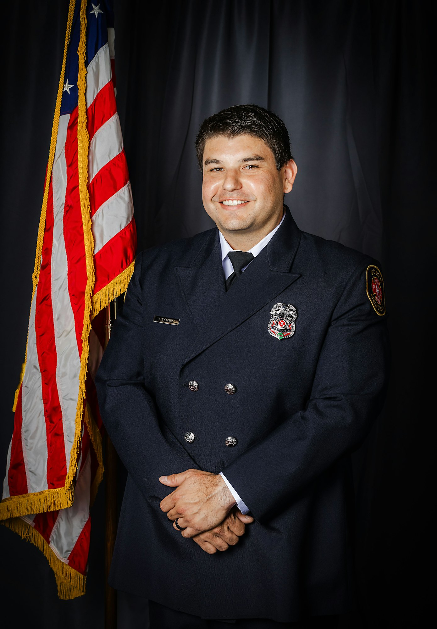 Firefighter Gomes, standing next to an American flag.