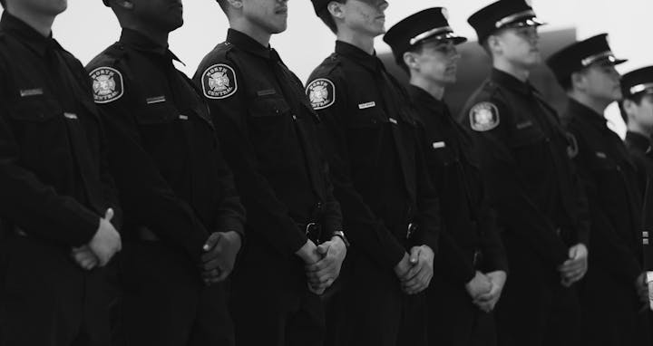 A black and white photo showing a line of police officers in uniform standing side by side.