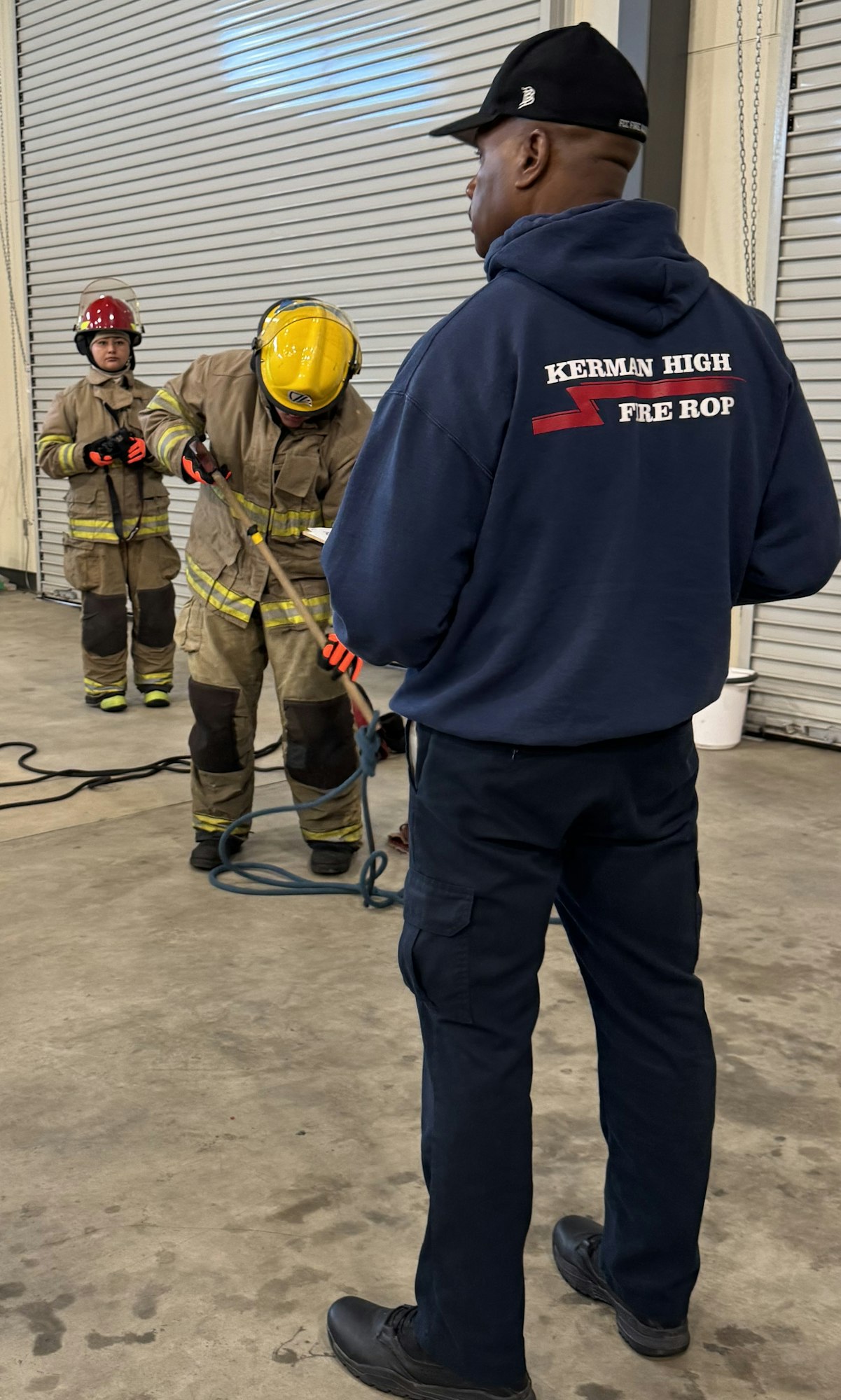 People in firefighting gear engaged in training or a drill in a garage space.